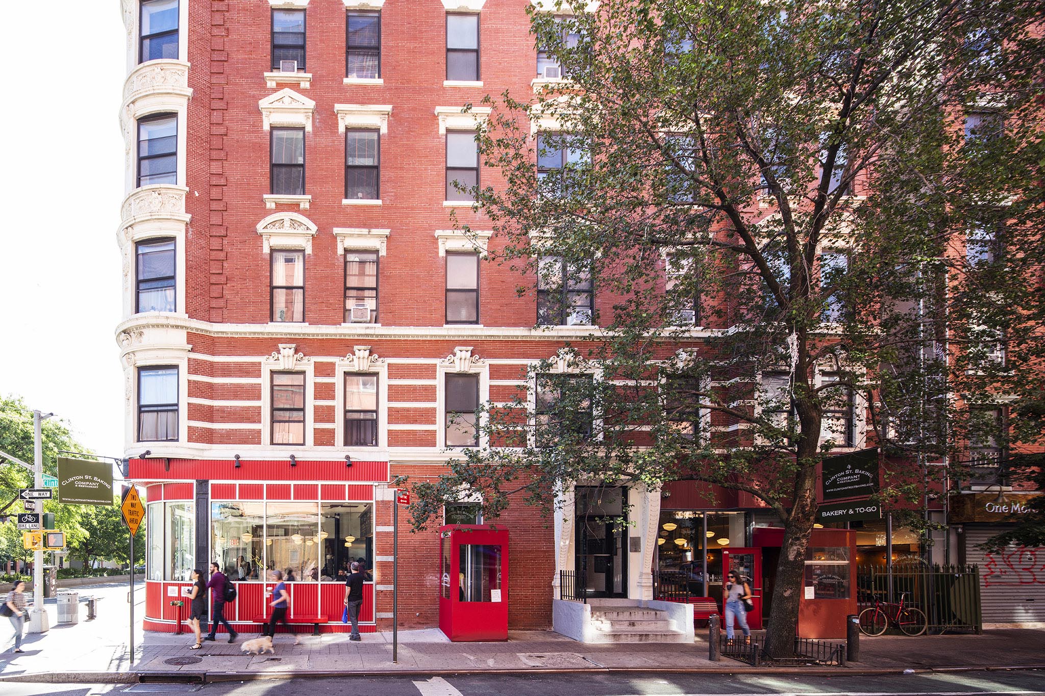 Sunny Storefront image on Clinton Street in NYC. There are 6 people passing by, a tree, and a bike.