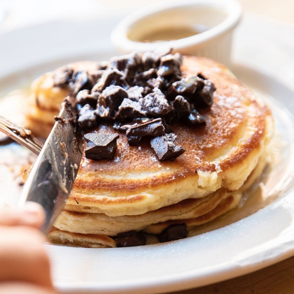 Chocolate chunk pancakes being cut into with a knife