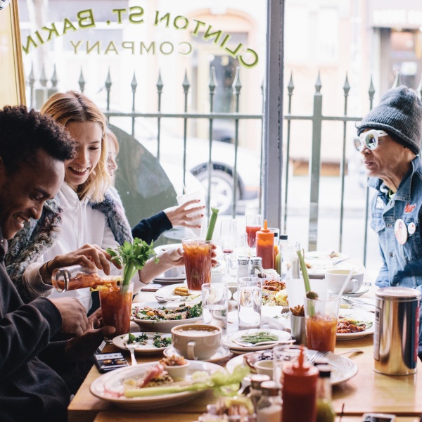 Friends having brunch in a sunny window booth drinking bloody marys.