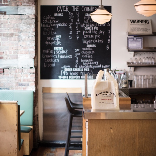 The empty bakery counter with a blackboard and brick wall in the background.